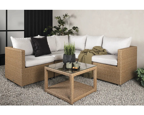 Trädgårdsgrupp med rottingsoffa, kuddar och glasbord på grus