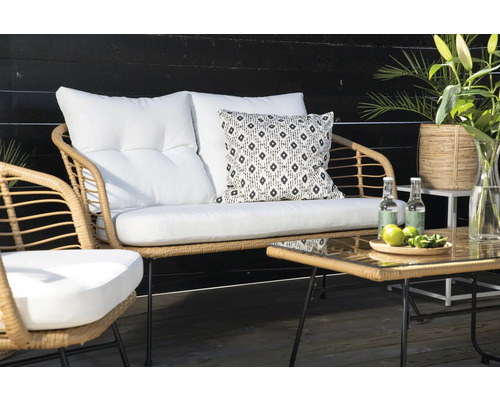 Trädgårdsmöbelset i rotting med bord, soffa och stol samt vita kuddar och dekoration