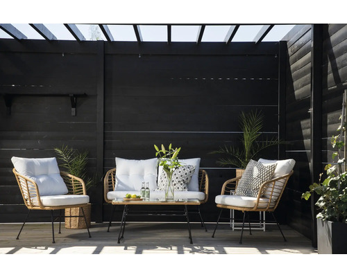 Terrassscen med rottingmöbler, bestående av två fåtöljer, en tvåsitssoffa och ett bord framför ett mörkt trästaket