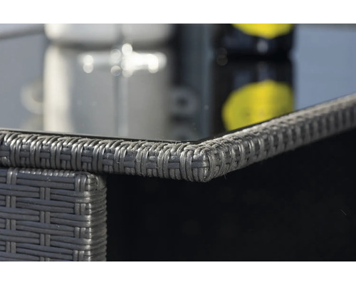 Detaljbild av ett trädgårdsbord med rottingstruktur och glasskiva