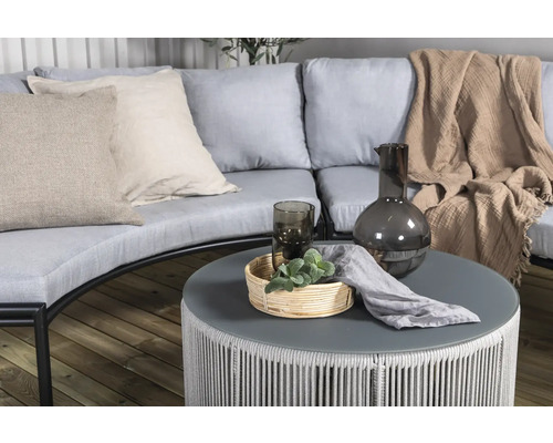 Miljöbild med trädgårdsmöbler, bestående av soffa, kuddar, bord, dekorationer och textilier för utomhusbruk