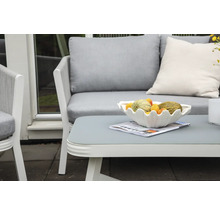 Terrass med trädgårdsmöbler: soffa, fåtölj och bord med fruktskål och tidning