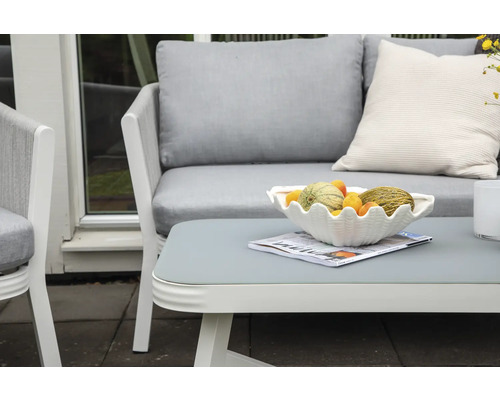 Terrass med trädgårdsmöbler: soffa, fåtölj och bord med fruktskål och tidning