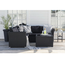 Trädgårdsloungegrupp med rottingsoffa, bord och dekorativa kuddar på en terrass