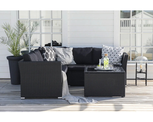 Trädgårdsloungegrupp med rottingsoffa, bord och dekorativa kuddar på en terrass