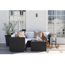 Terrass med rottingmöbler, kuddar, bord och växt i en kruka.