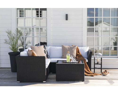 Terrass med rottingmöbler, kuddar, bord och växt i en kruka.