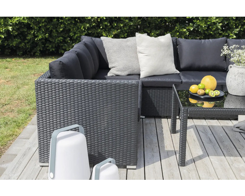 Trädgårds loungeset med rottingyta, soffbord med glasskiva och två lyktor på en träterrass