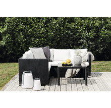 Trädgårdsscen med rottinglounge, bord, dekoration och lyktor på en träaltan.