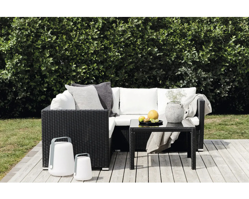 Trädgårdsscen med rottinglounge, bord, dekoration och lyktor på en träaltan.