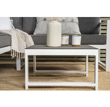 Vitt soffbord med grå bordsskiva och dekoration på en matta