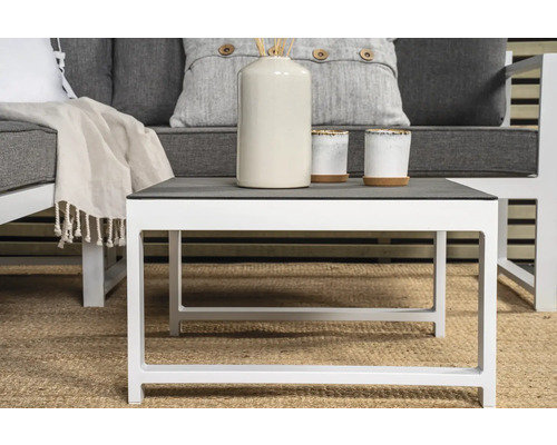 Vitt soffbord med grå bordsskiva och dekoration på en matta