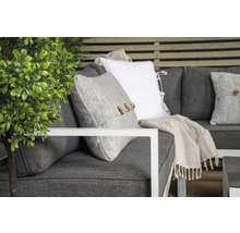 Närbild av en grå soffa med kuddar och växt