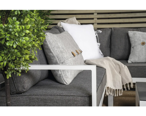 Närbild av en grå soffa med kuddar och växt