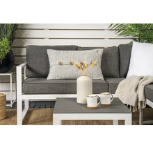 Trädgårdsscen med soffa, kudde med knappar, bord, vas, koppar och dekoration