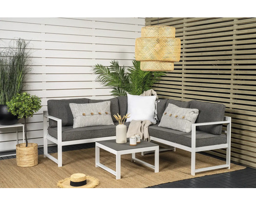 Trädgårdsscen med loungegrupp, soffbord och hängande rottinglampa framför insynsskydd