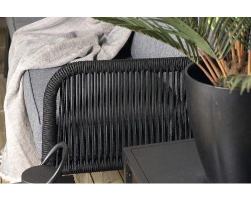 Detaljbild av en utomhusfåtölj med växter och sidobord