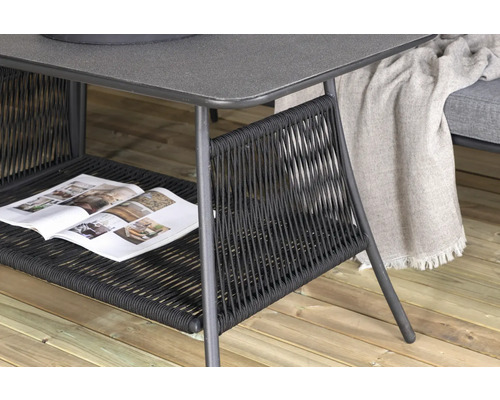 Detaljvy av ett trädgårdsbord med flätad hylla och tidning