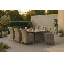 Trädgårdsscen med matbord och rottingstolar på en terrass med växter och belysning.