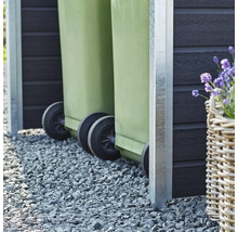 Två gröna soptunnor i ett soptunneskydd på grus