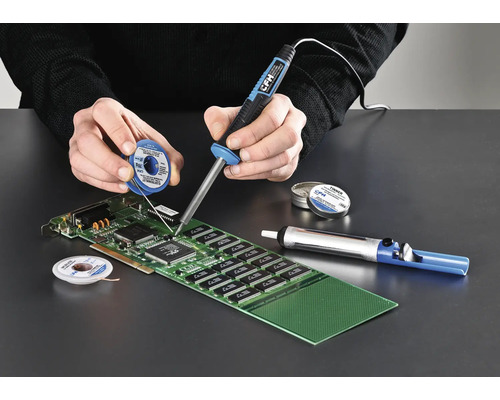 Person löder ett kretskort med en lödkolv, lödtenn och avlödningspump.