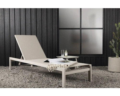 Miljöbild med en trädgårdsstol, ett sidobord, en dryck, en bok och en filt utomhus