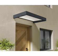 Modernt entrétak i antracit med vit panel monterat ovanför en ytterdörr i trä på en putsad fasad.