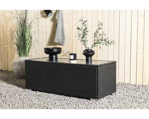 Miljöbild med ett svart trädgårdsbord med glasskiva, dekorerat med en skål, ett ljus och en vas.