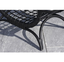 Detaljvy av en svart rottingfåtölj med metallram