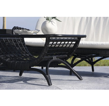 Scen med svart rottingfåtölj och soffa med vita kuddar