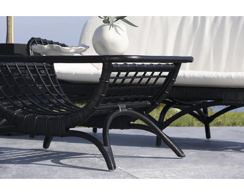 Scen med svart rottingfåtölj och soffa med vita kuddar