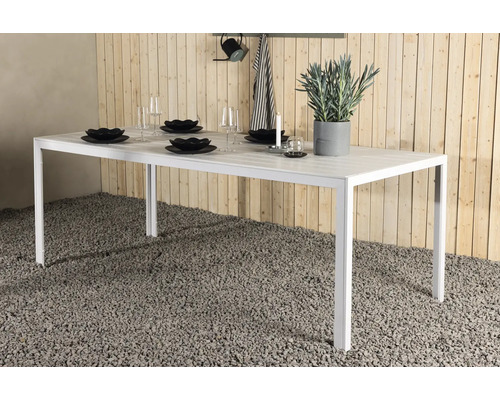 Dukat vitt trädgårdsbord med dekoration och porslin.