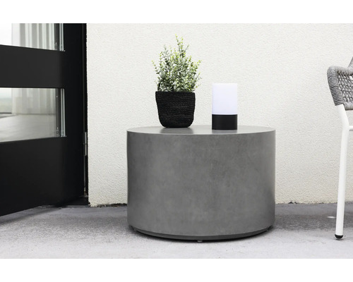 Runt betongbord med växt och lampa