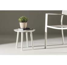 Sidobord med växt, bok och glasögon bredvid en stol