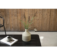 Dekorativ vas med gräs på ett trädgårdsbord