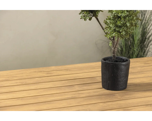 Dekorativ konstgjord växt i kruka på ett träbord