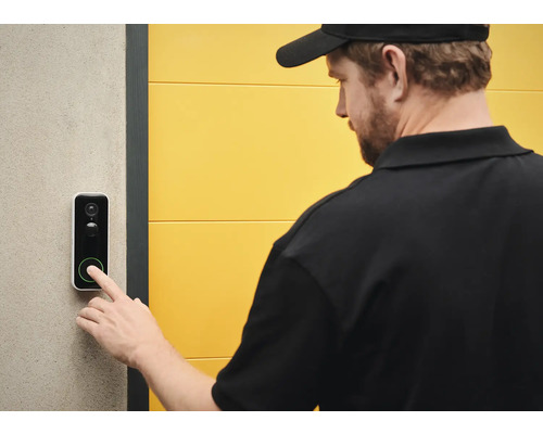 En person trycker på en dörrklocka med kamerafunktion.