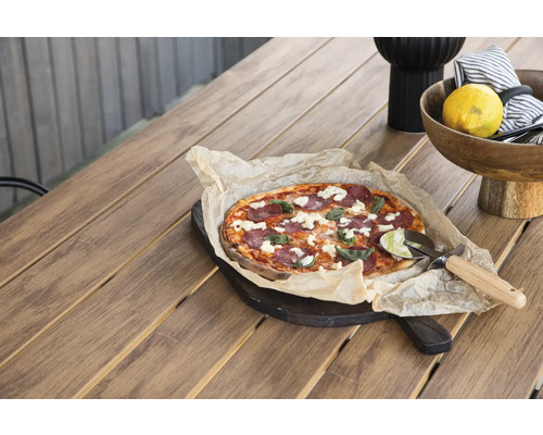 Scen med pizza på ett träbord, kompletterat med en serveringsskål, en citron och en pizzasax.