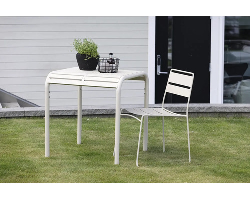 Trädgårdsscen med trädgårdsbord och trädgårdsstol på gräsmatta