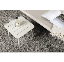 Fyrkantigt trädgårdsbord i metall med drycker och tidskrift