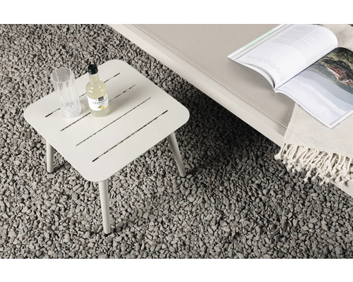 Fyrkantigt trädgårdsbord i metall med drycker och tidskrift