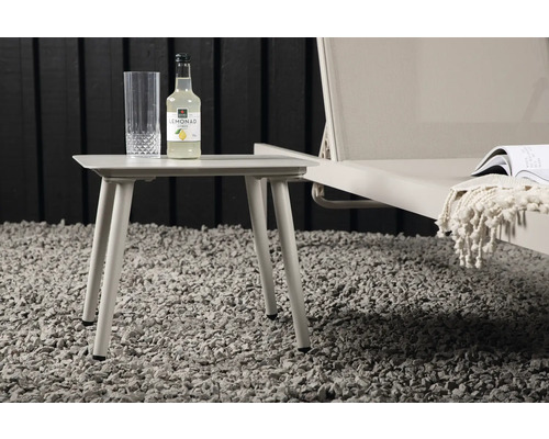 Sidobord med en flaska dryck och ett glas bredvid en solstol