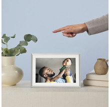 Digital fotoram med foto av en far och hans son på ett bord, bredvid en vas med eukalyptus och en hand som pekar på ramen.