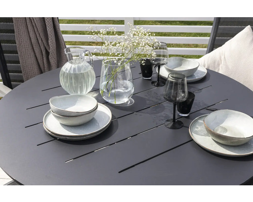 Dukat runt trädgårdsbord med porslin, glas, karaff och blommor