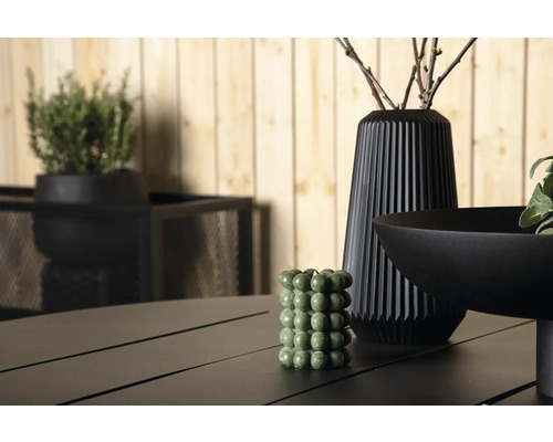 Dekorativ scen med ett grönt bubbel-ljus, en vas och en skål på ett bord