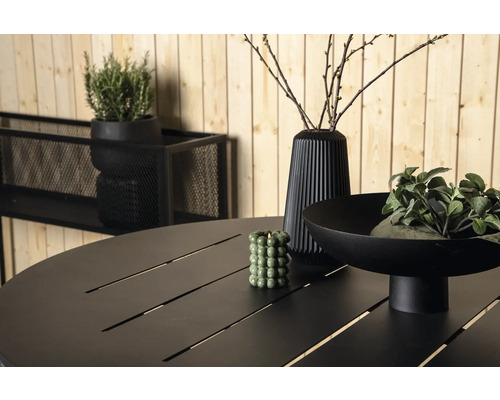 Närbild av ett trädgårdsbord med dekoration, inklusive en vas och växter