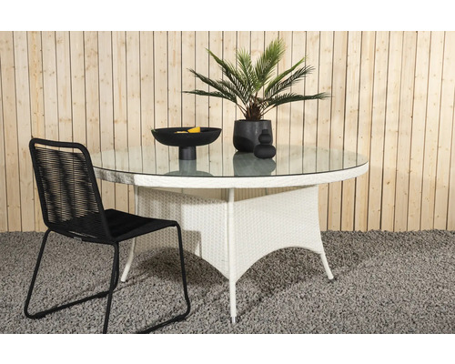 Trädgårdsscen med runt glasbord, rottingstol och dekorativa tillbehör för utomhusbruk