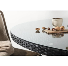 Detaljbild av ett runt trädgårdsbord med glasskiva och rottingkant.