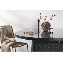 Trädgårdsscen med rottingbord, glasskiva, dekorationer och stol med filt