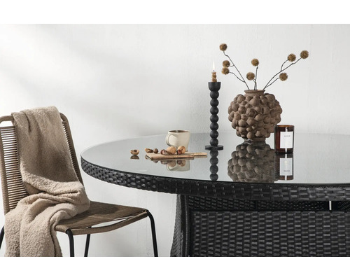 Trädgårdsscen med rottingbord, glasskiva, dekorationer och stol med filt